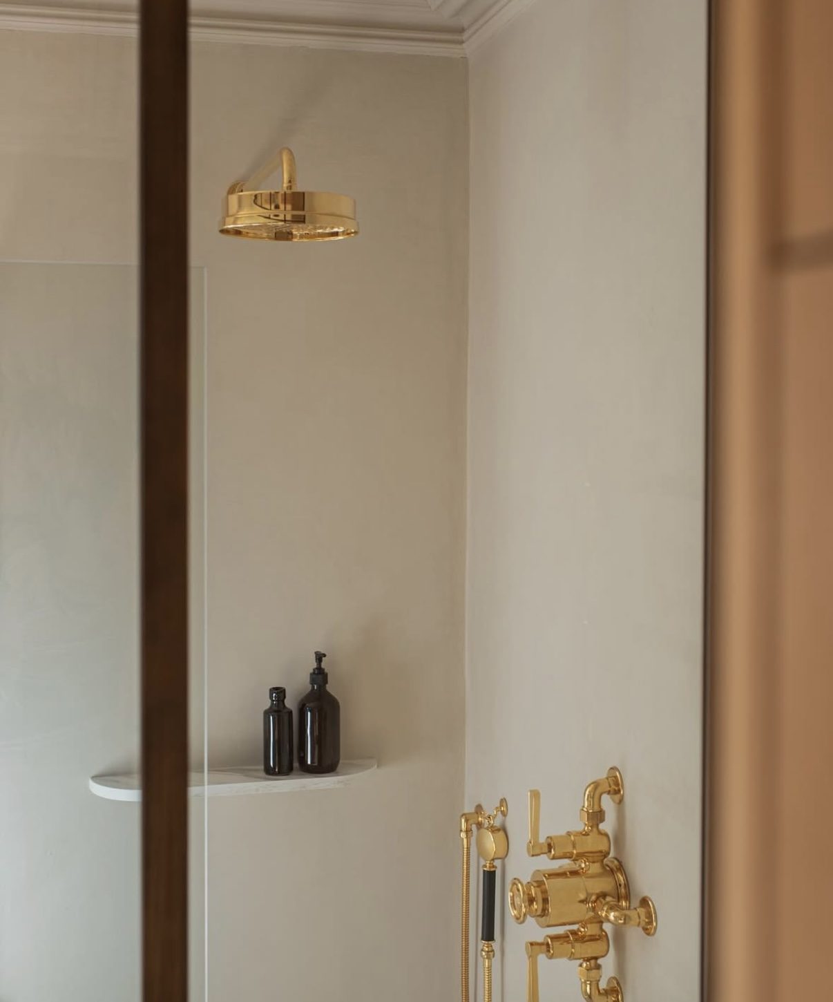 Shower enclosure with seamless microcement walls and brass fittings