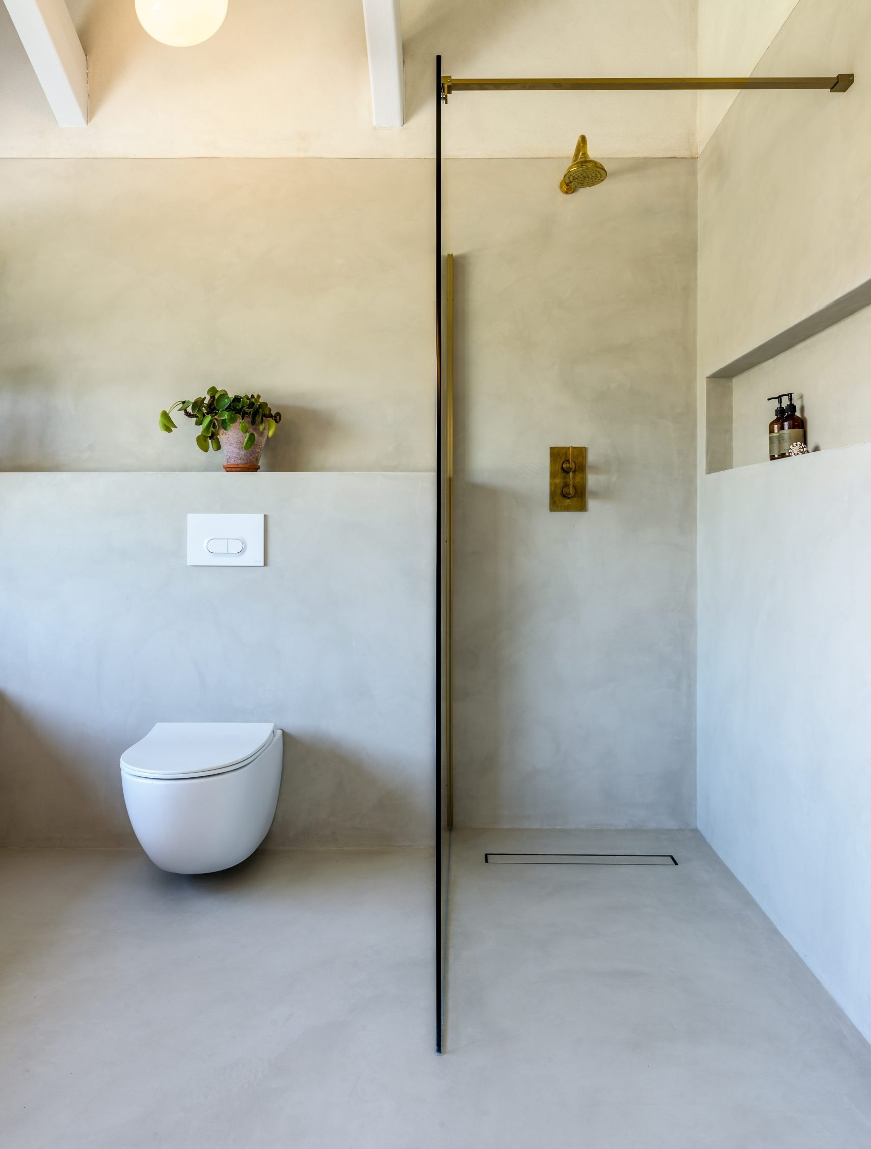 Bathroom finished in seamless microcement with brass shower fittings