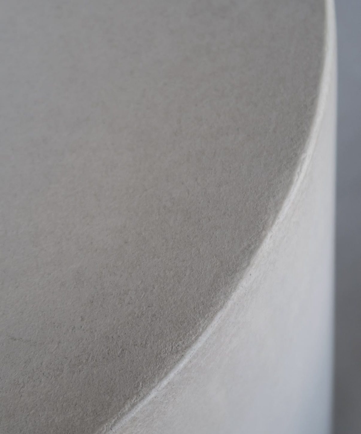 Close view of a curved microcement edge, the surface continuing unbroken around the radius